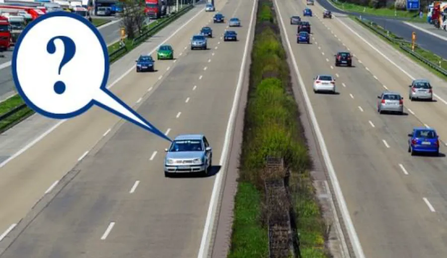 Under what conditions is a driver of a passenger car allowed to drive in the far left lane on a road with a median strip?